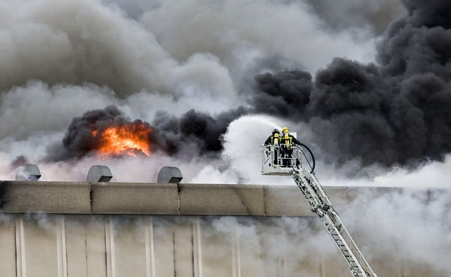 Una grúa eleva a dos bomberos para que puedan echar agua sobre el tejado de la nave industrial.  / JESÚS J. MATÍAS