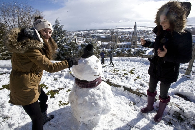 El temporal de nieve ofreció imágenes como esta, en la que dos jóvenes disfrutan haciendo un muñeco de nieve con la Catedral al fondo.
