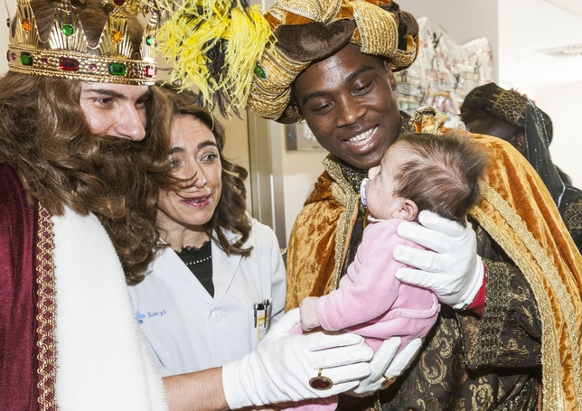 Gaspar y Baltasar, con un niño en brazos, durante su visita a los niños hospitalizados en el HUBU.  / ALBERTO RODRIGO