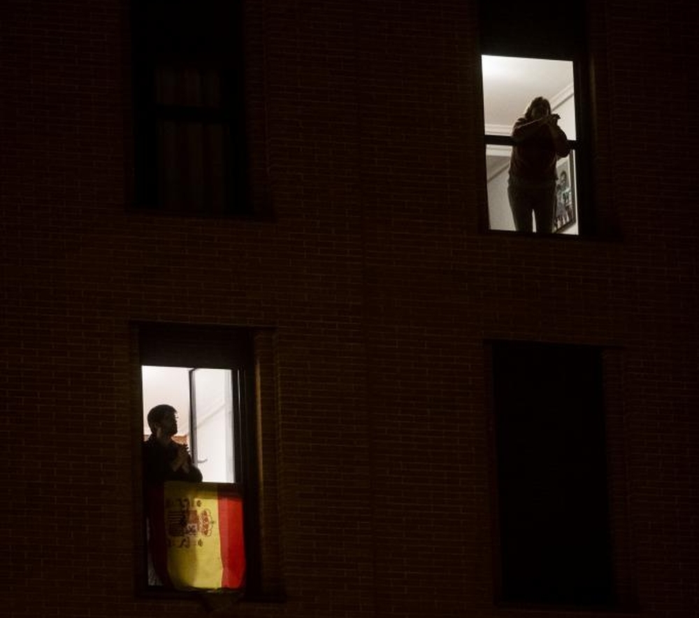 Vecinos asomados a la ventana para aplaudir en homenaje a la labor de los profesionales sanitarios.   / ALBERTO RODRIGO