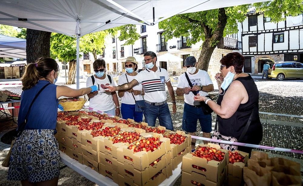 Unos clientes comprueban cuáles son las cerezas que más les gustan antes de llevarse varias cajas a casa.