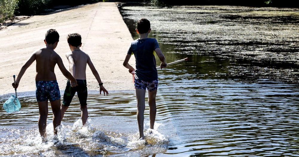 Los niños disfrutan del agua del río en Puentedura cogiendo cangrejos y peces con sus redes. 