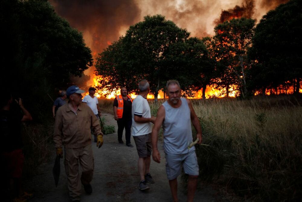 Men walk away from a wildfire in Verin  / FELIPE CARNOTTO