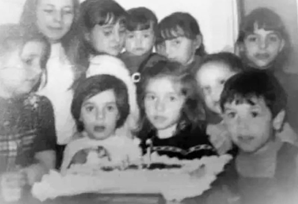 Un grupo de egeberas se apiñan ante la tarta en un cumpleaños de 1974. 