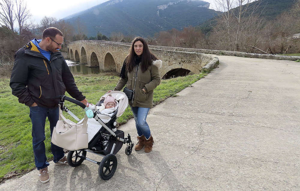 Saúl Alonso y Maider Lastra con la pequeña Laia ante el puente medieval de Trespaderne. 