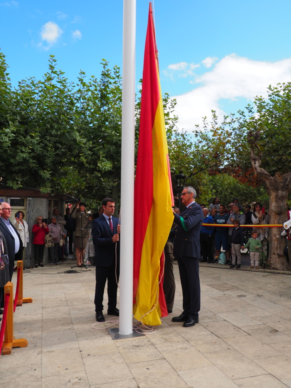 El alcalde de Villarcayo, Adrián Serna (i.), iza la bandera de España.