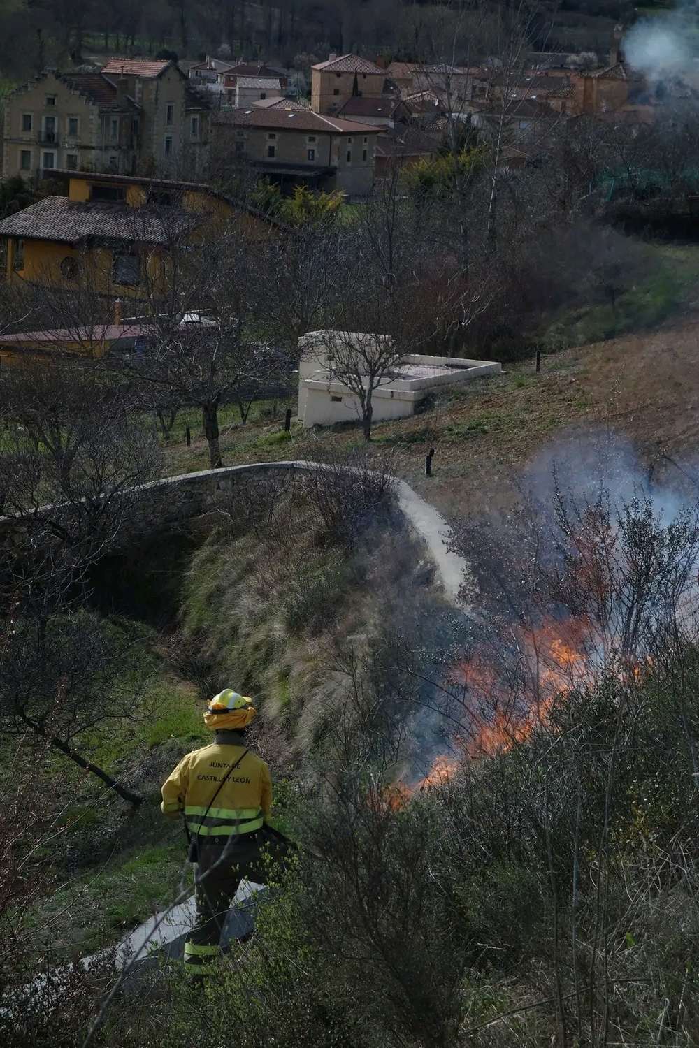 Un bombero forestal trabaja con la localidad de Puente Arenas de fondo 