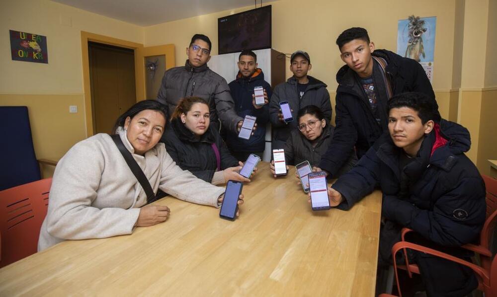 Un grupo de migrantes de Colombia y Venezuela, en la casa de acogida de las Hijas de la Caridad refrescando su teléfono móvil en busca de una cita que no llega.