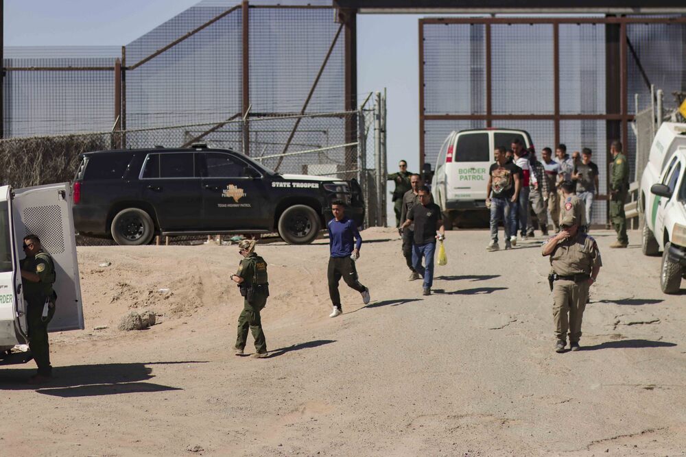 Migrantes detenidos son llevados hoy por miembros de la Patrulla Fronteriza estadounidense a un vehículo, junto al muro fronterizo en El Paso, Texas.